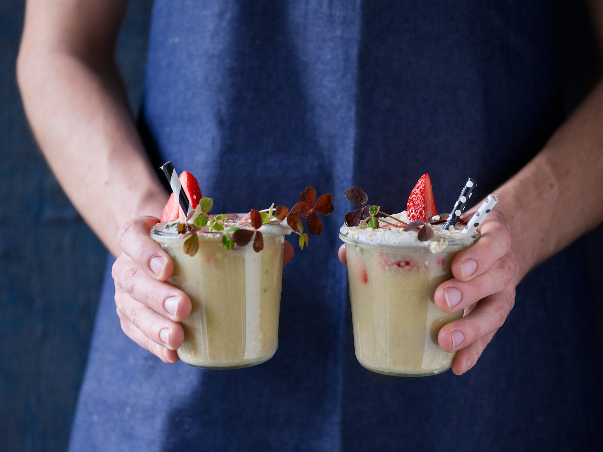 Žmogus laiko du avižų kokteilius su braškėmis